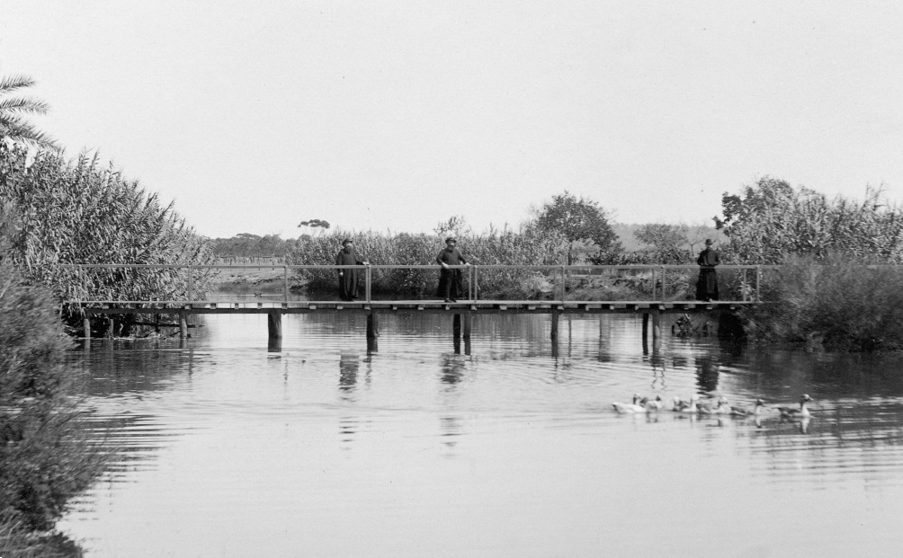 Monks at New Norcia walking on a bridge over the river.